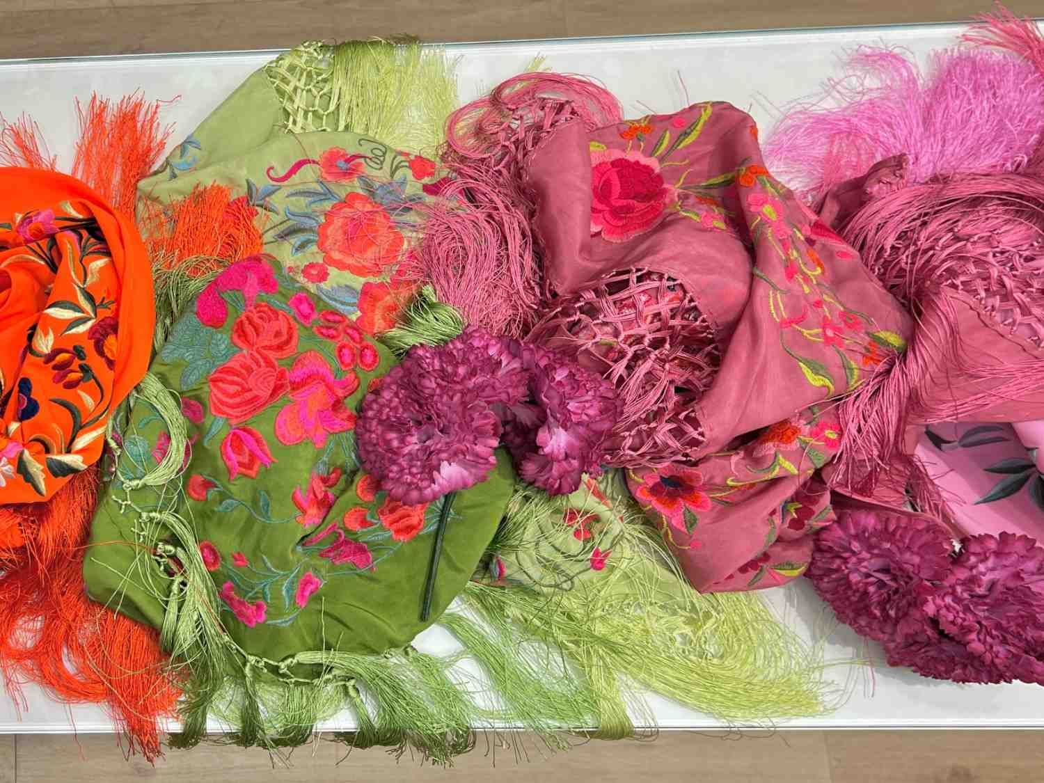 Telas coloridas dobladas en naranja, verde, rosa y morado dispuestas en capas superpuestas.