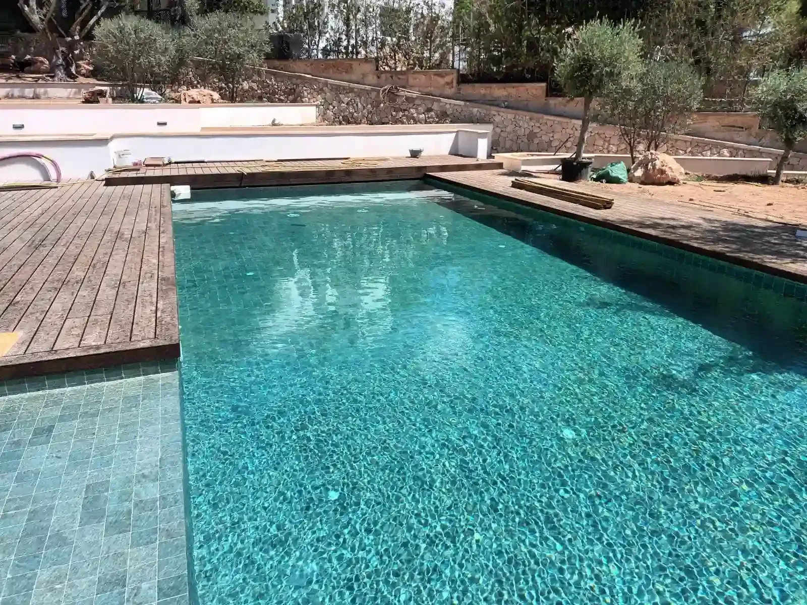 Trabajadores reparando una piscina vacía junto a otra piscina llena en un patio interior