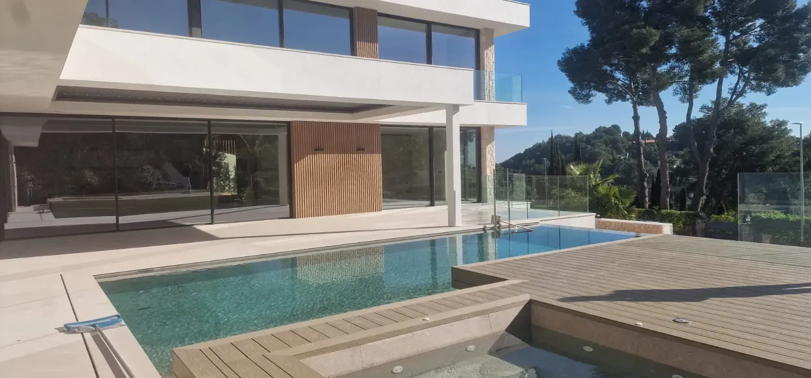 Piscina rectangular azul rodeada de azulejos beige en una terraza en la azotea.