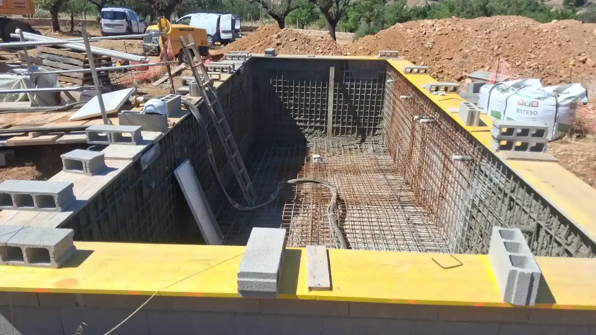 Piscina o estanque rectangular de hormigón vacío, con el fondo revestido de baldosas gris oscuro y paredes laterales elevadas