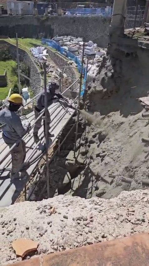 Dos trabajadores reparan el equipo de la piscina junto a una piscina azul