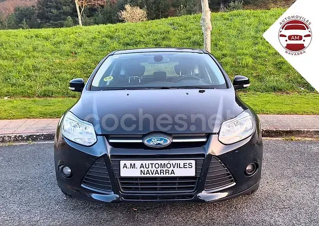 Un coche Ford negro está aparcado frente a una colina cubierta de hierba.