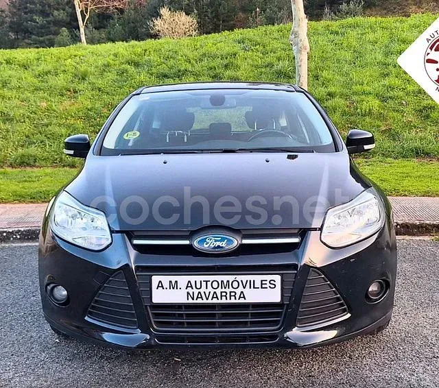 Un coche Ford negro está aparcado frente a una colina cubierta de hierba.
