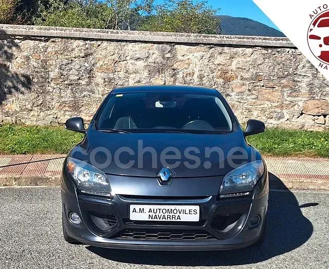 Un coche negro está aparcado delante de un muro de piedra.
