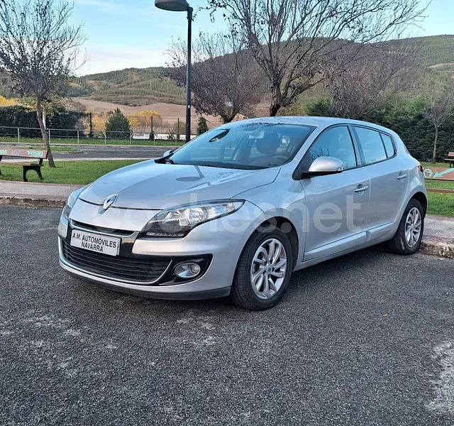 Un coche plateado está aparcado al costado de la carretera.