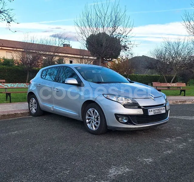 Un coche plateado está aparcado al costado de la carretera.
