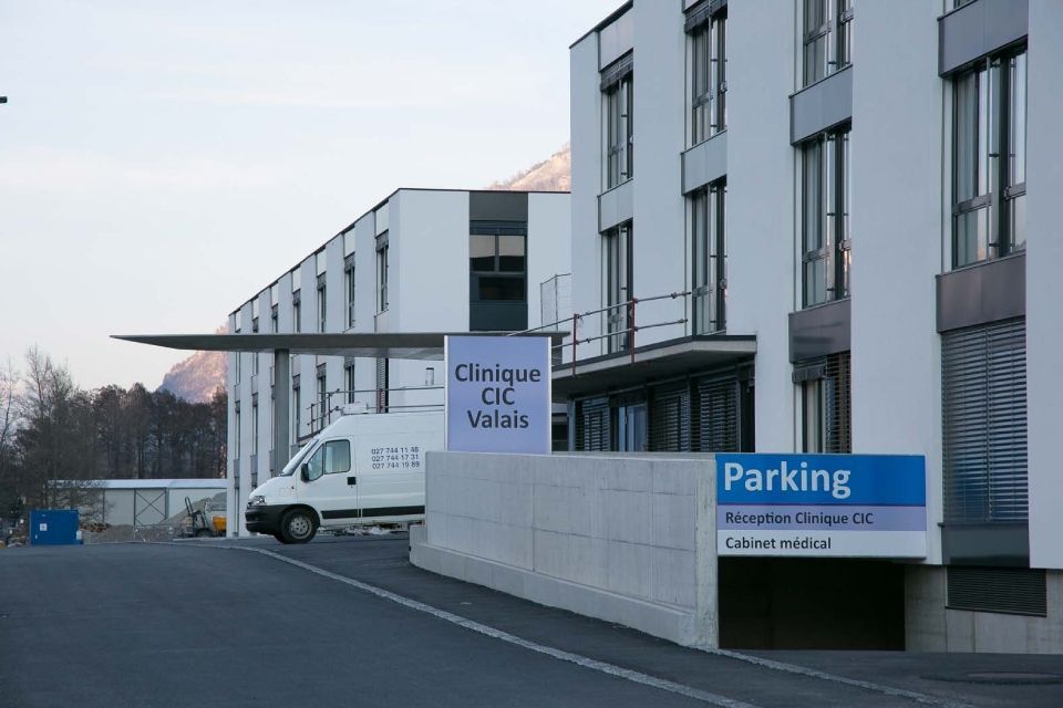 Une camionnette blanche est garée devant un immeuble avec un panneau de stationnement.