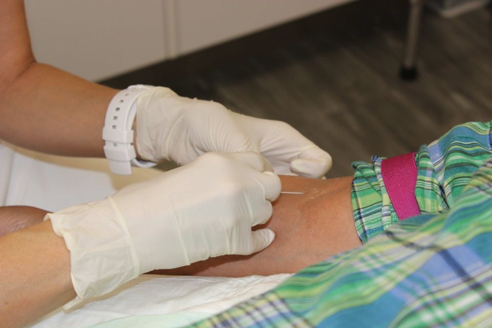 Une personne portant des gants reçoit une injection dans le bras.