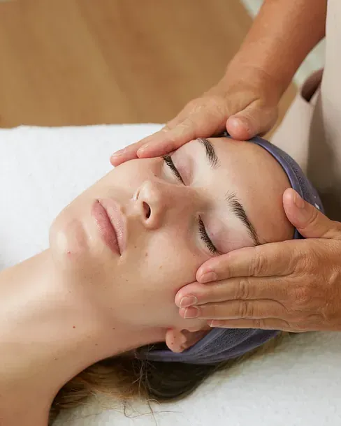Una mujer está recibiendo un masaje facial en un spa.
