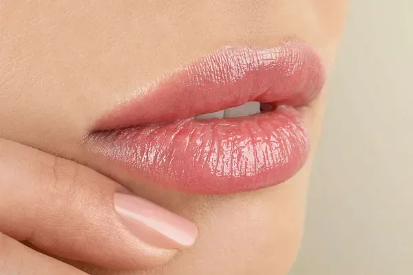 Un primer plano de los labios de una mujer con lápiz labial rosa.