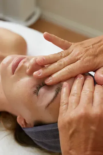 Una mujer está recibiendo un masaje facial en un spa.