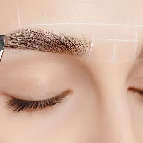 Una mujer se está haciendo un maquillaje para las cejas.