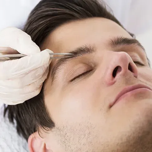 Un hombre se está haciendo recortar las cejas por un médico.