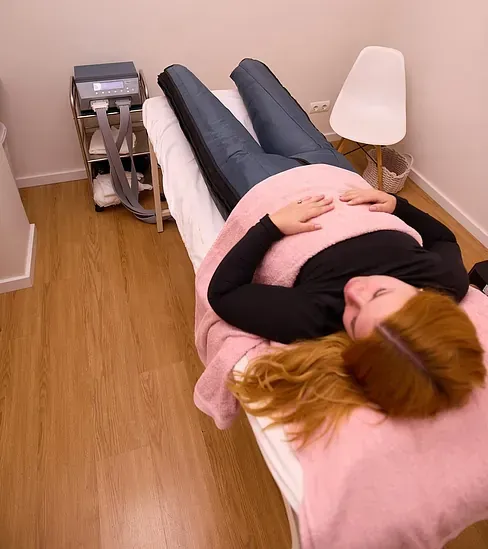 Una mujer está acostada en una cama con una manta rosa.