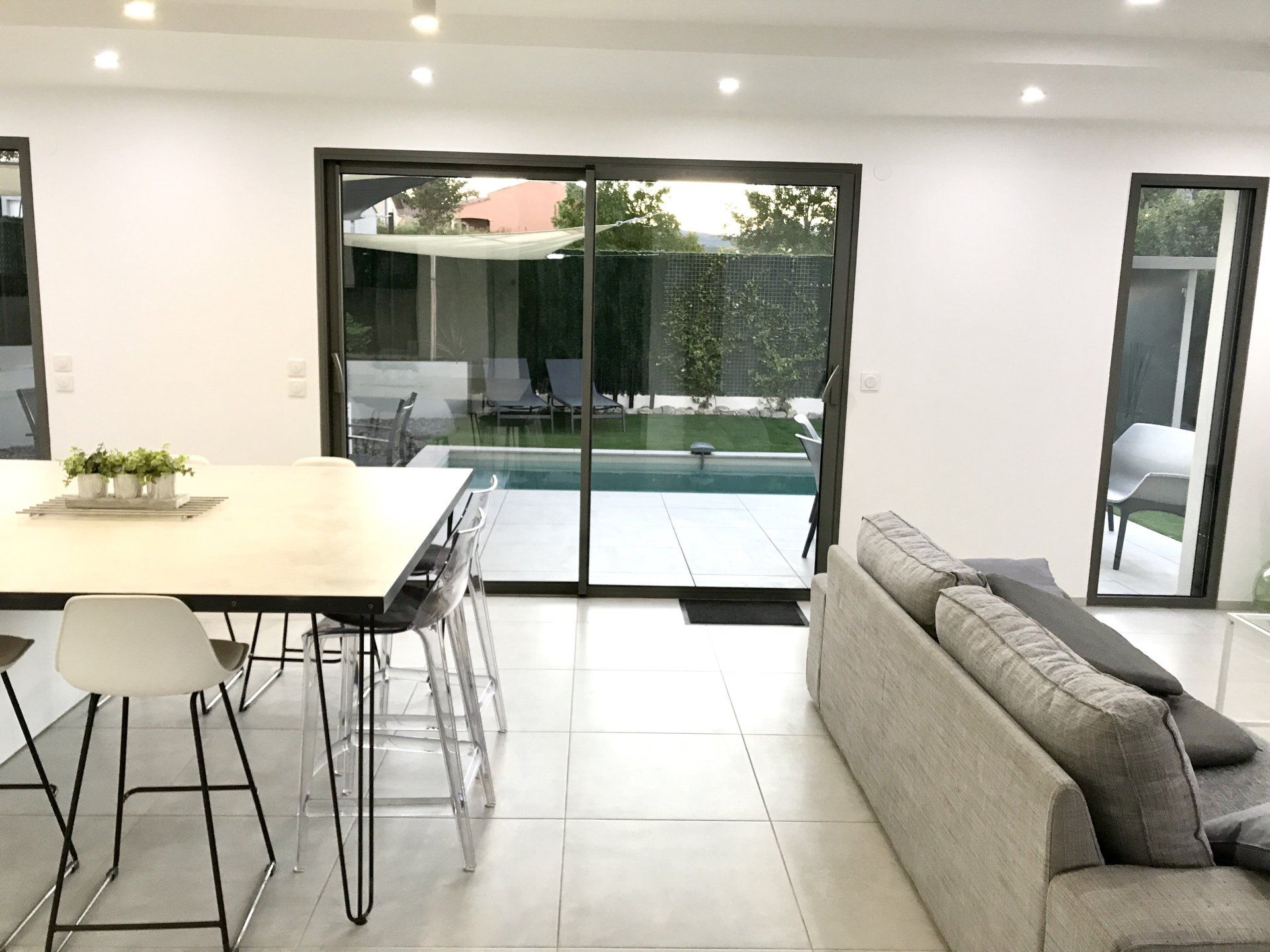 Pièce à vivre et salle à manger moderne et lumineuse, à aire ouverte, avec portes coulissantes en verre donnant sur une terrasse.