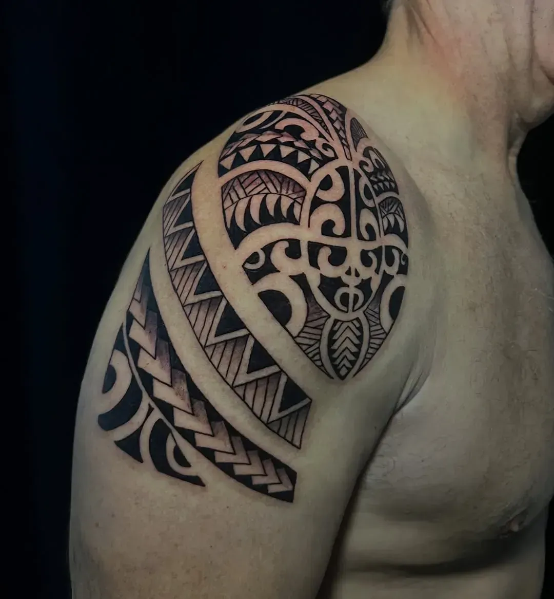 Tatuaje en el hombro y la parte superior del brazo; diseño polinesio con tinta negra sobre piel desnuda.
