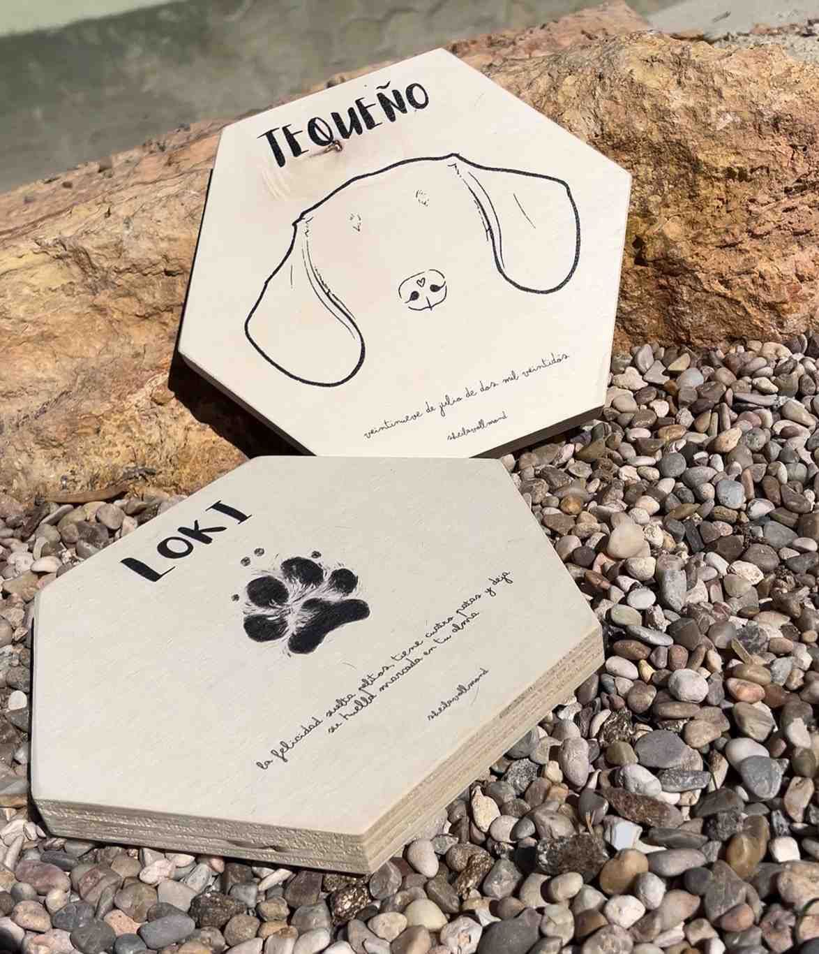 Dos carteles de madera con nombres de mascotas y dibujos: “Tiaño” con cara de perro y “Loki”