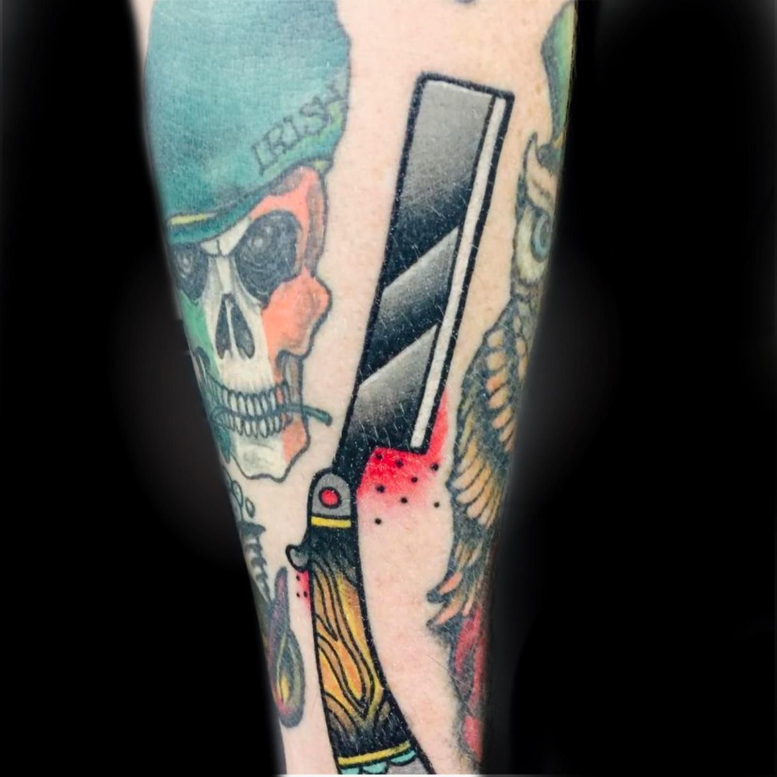 Tatuaje de una calavera en una boina irlandesa, una navaja de afeitar y un búho en la piel.