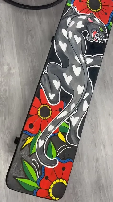 Estuche negro con una pantera gris adornada con formas de corazón y acentos florales rojos.