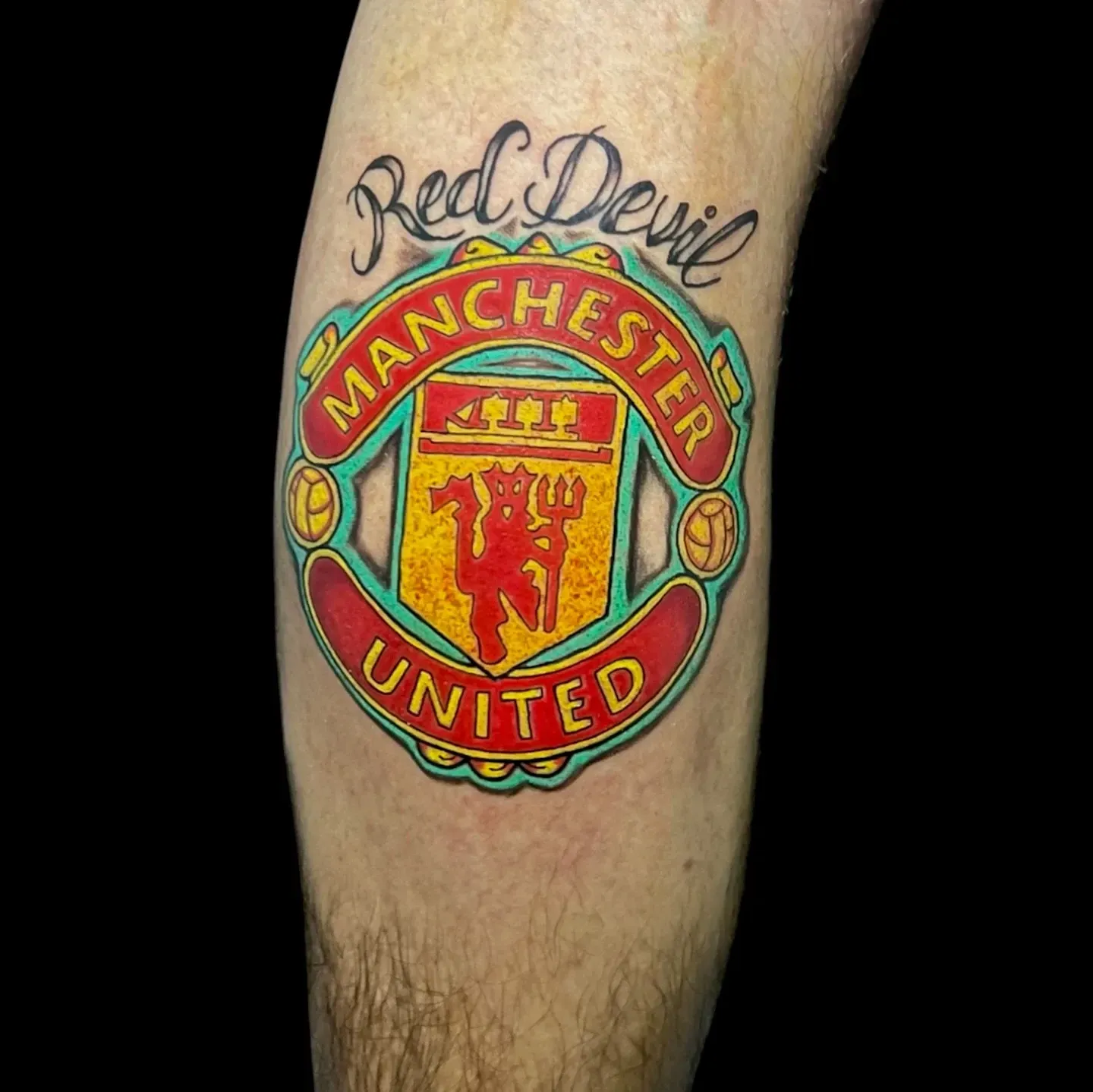 Tatuaje del Manchester United, un escudo colorido con la escritura 