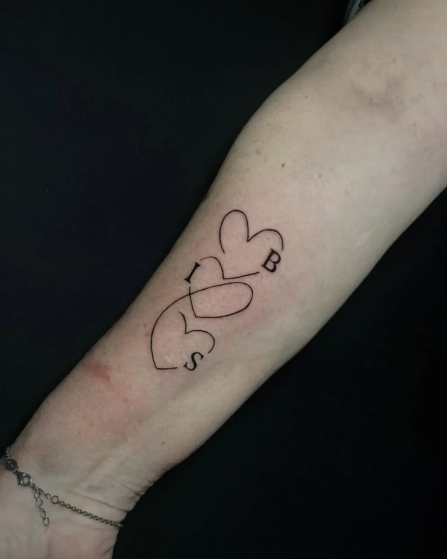 Tatuaje de tres corazones conectados, con las letras 