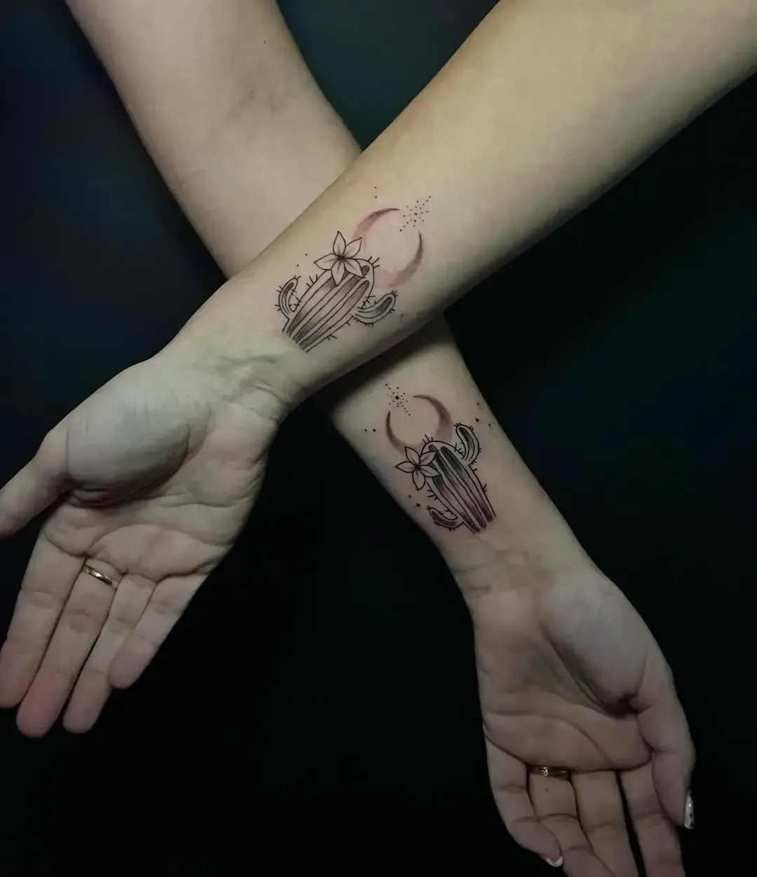 Dos muñecas con tatuajes de cactus y luna a juego.