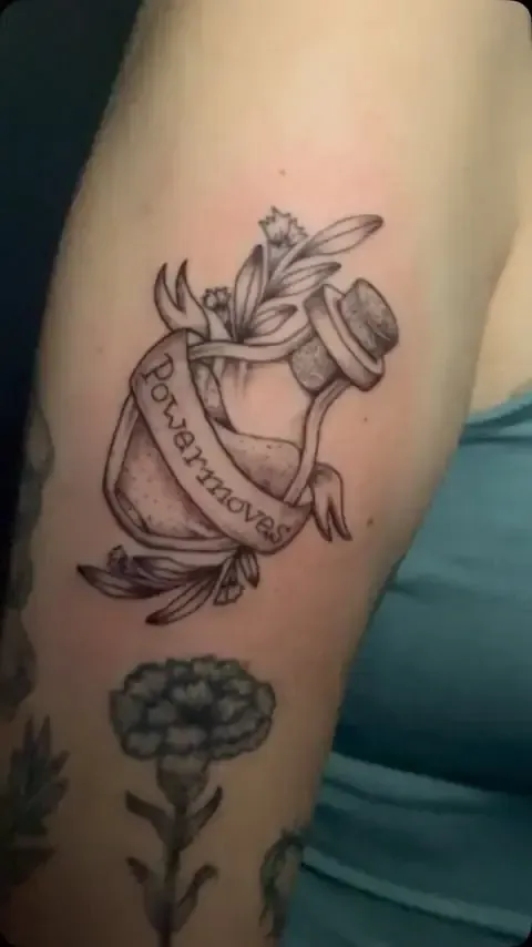 Tatuaje en el brazo: una botella de poción con la leyenda 