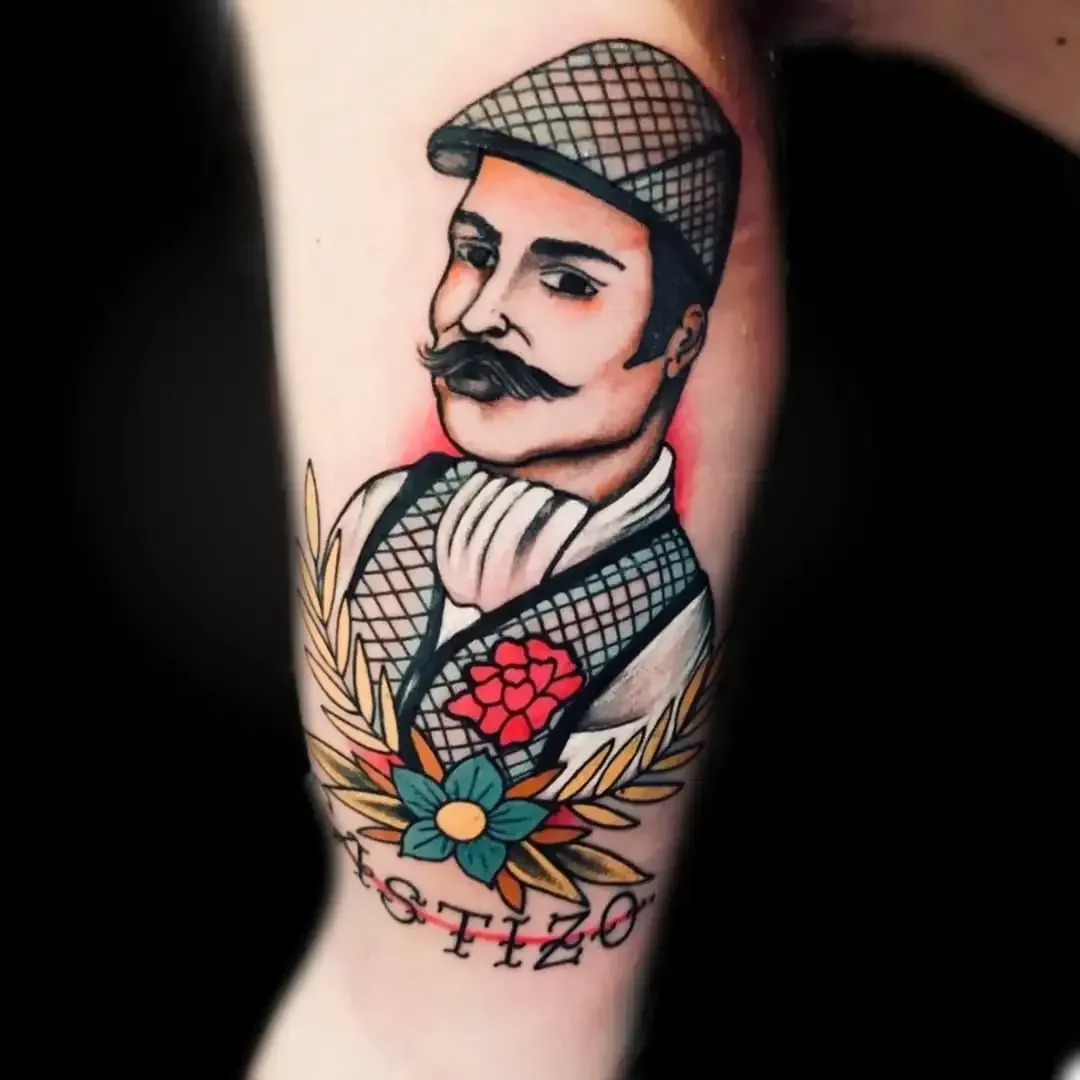 Tatuaje de un hombre con gorra plana y chaleco, adornos florales, texto 