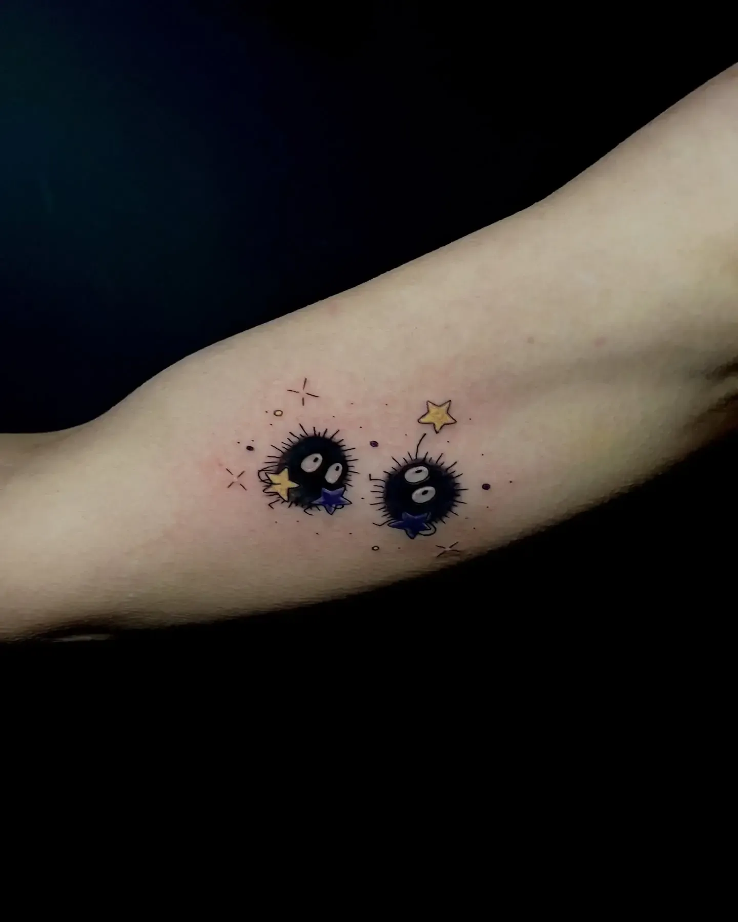 Dos tatuajes de duendes de hollín con estrellas en un brazo.
