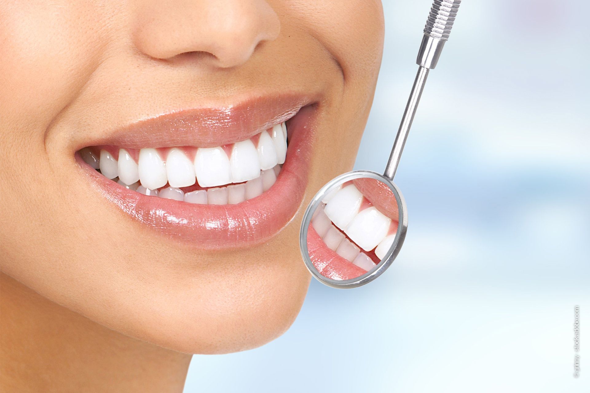 Eine Frau mit einem schönen Lächeln und einem kleinen Spiegel für die Zähne