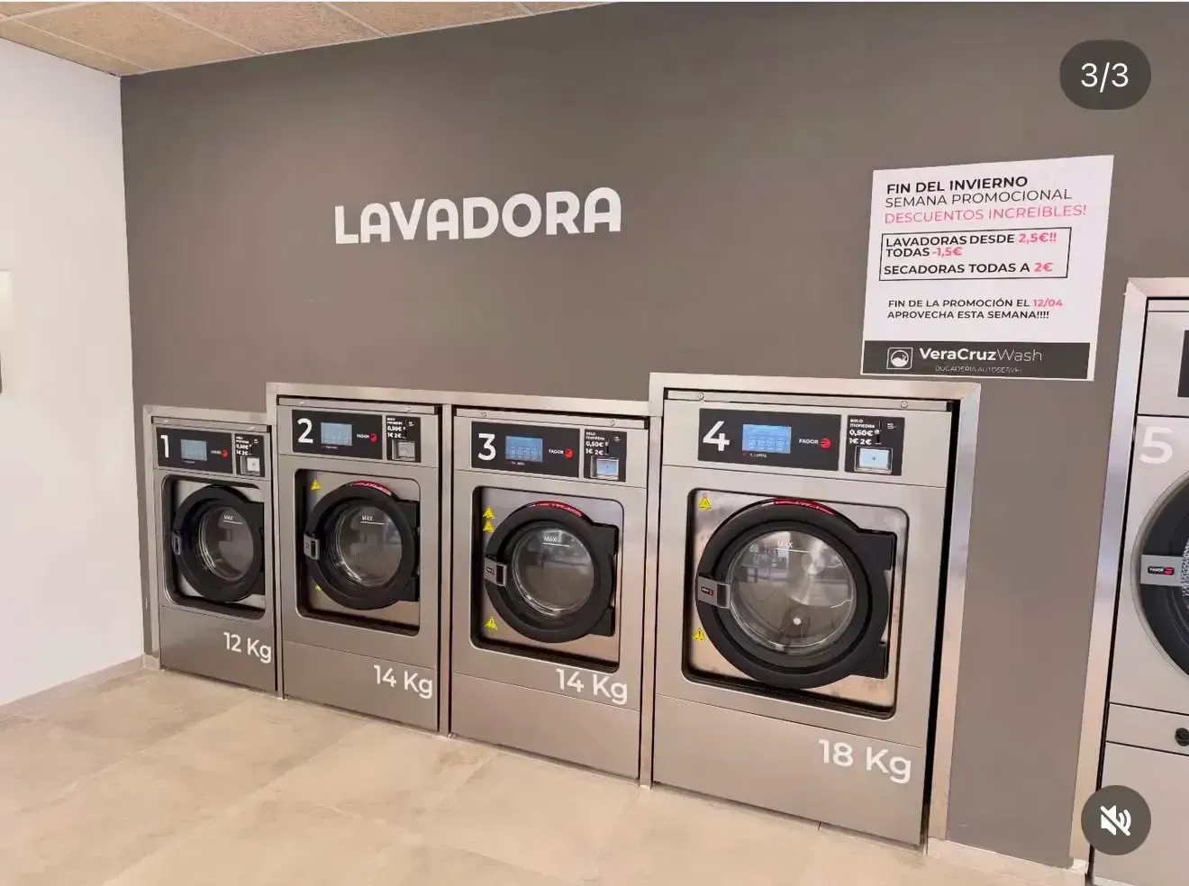Lavandería con cuatro lavadoras de carga frontal etiquetadas como LAVADORA, numeradas y apiladas junto a una pared.