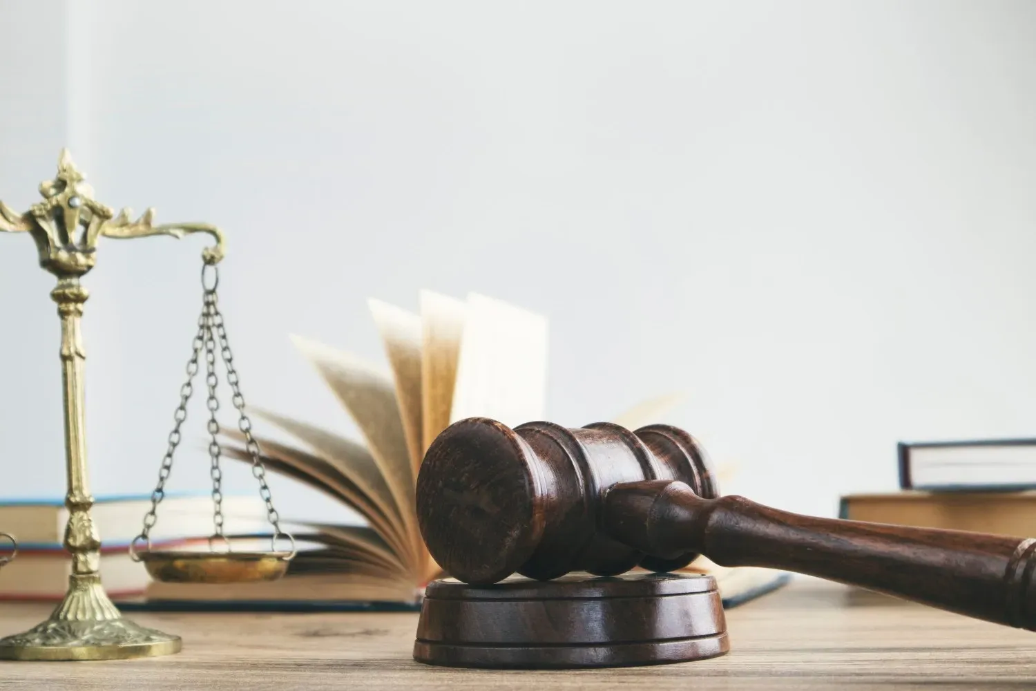 Balanza legal, libro abierto y mazo sobre un escritorio en un despacho de abogados.