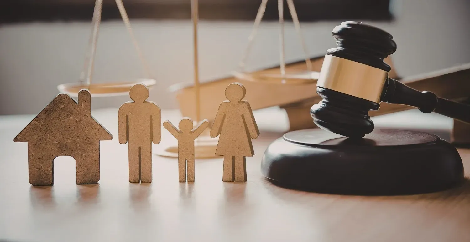 Figuras de madera de una familia y un mazo sobre un escritorio, lo que sugiere un caso de derecho familiar o de custodia.