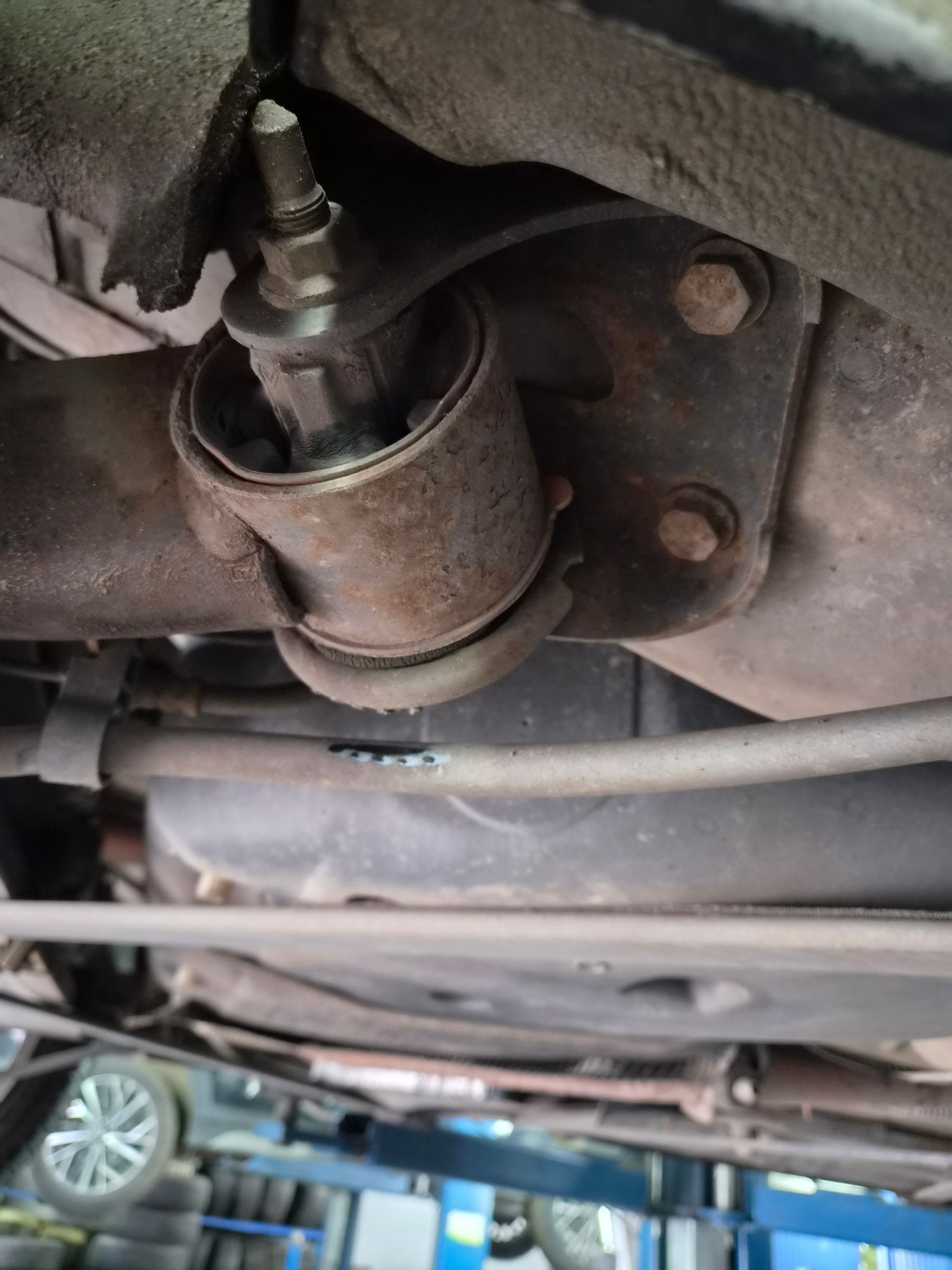 Gros plan sur une bague de suspension et un boulon rouillés sous le véhicule