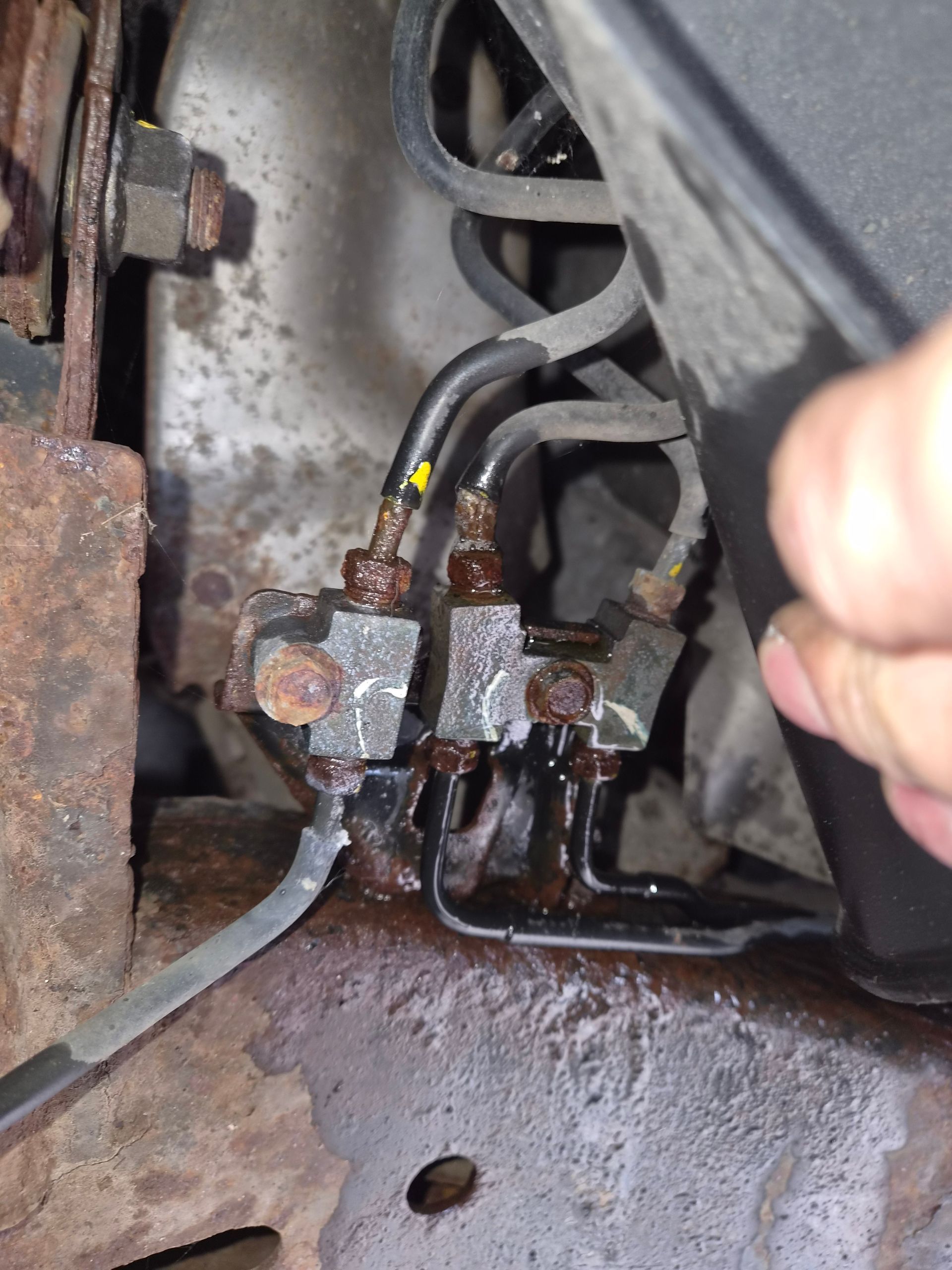 Relais électrique rouillé et fils montés sur une surface métallique, avec une main qui ajuste un câble à proximité