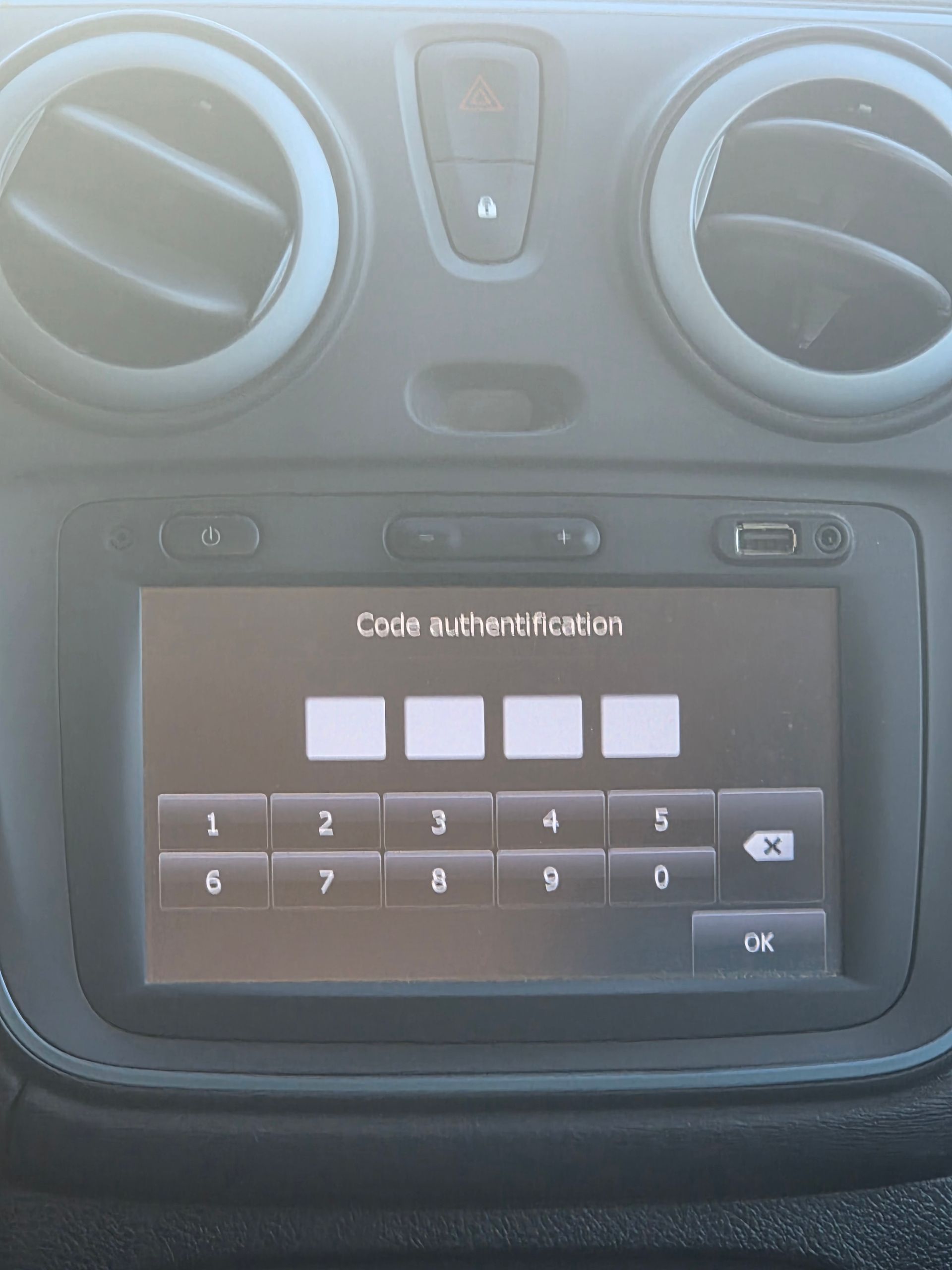 Écran tactile du tableau de bord d’une voiture affichant un clavier de saisie à quatre chiffres, avec les bouches d’aération au-dessus.