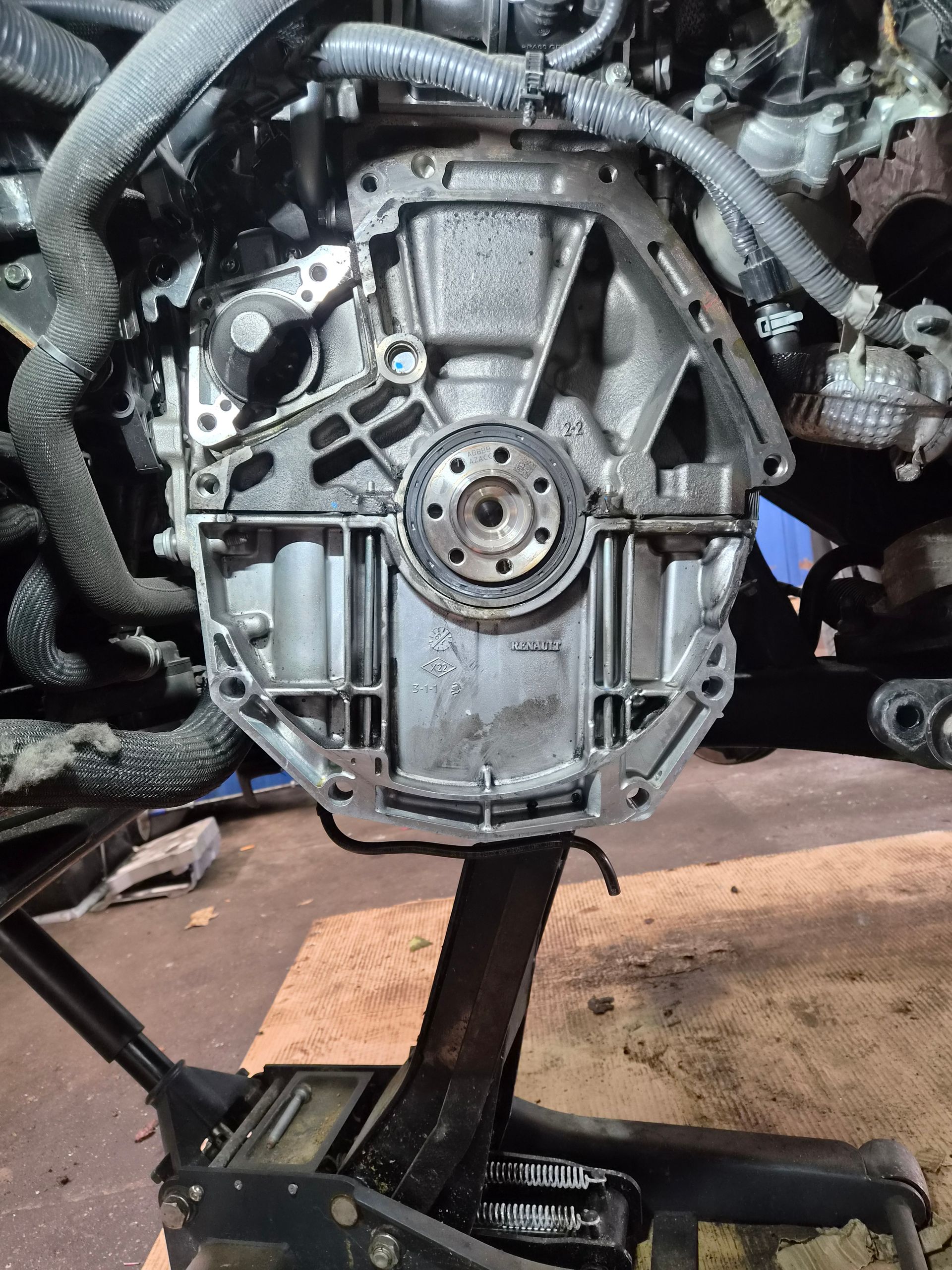 Vue rapprochée du carter de transmission d’un moteur de voiture, monté sur un pont élévateur dans un atelier