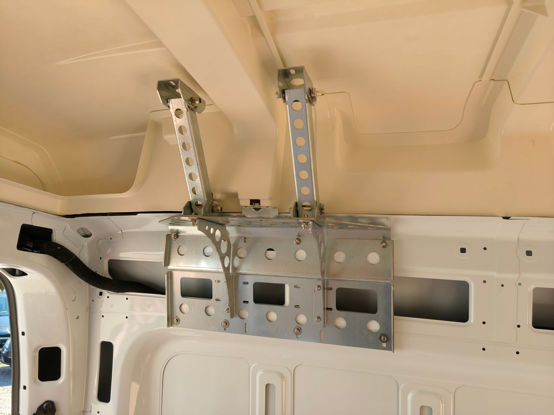 À l’intérieur d’un véhicule blanc, des supports et des rails métalliques sont fixés près du plafond.