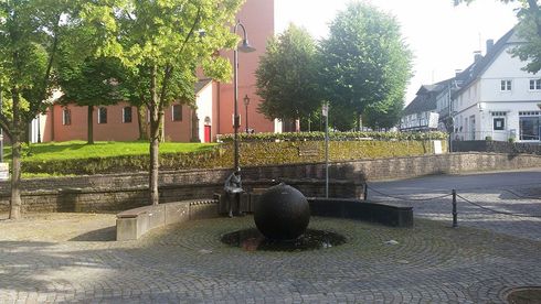 Ein Brunnen in einem Park mit einer Kirche im Hintergrund