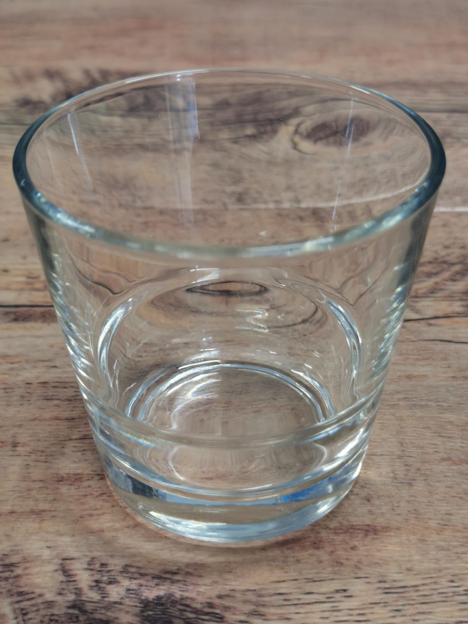 Tyhjä kirkas lasinen muki puisella pöydällä.