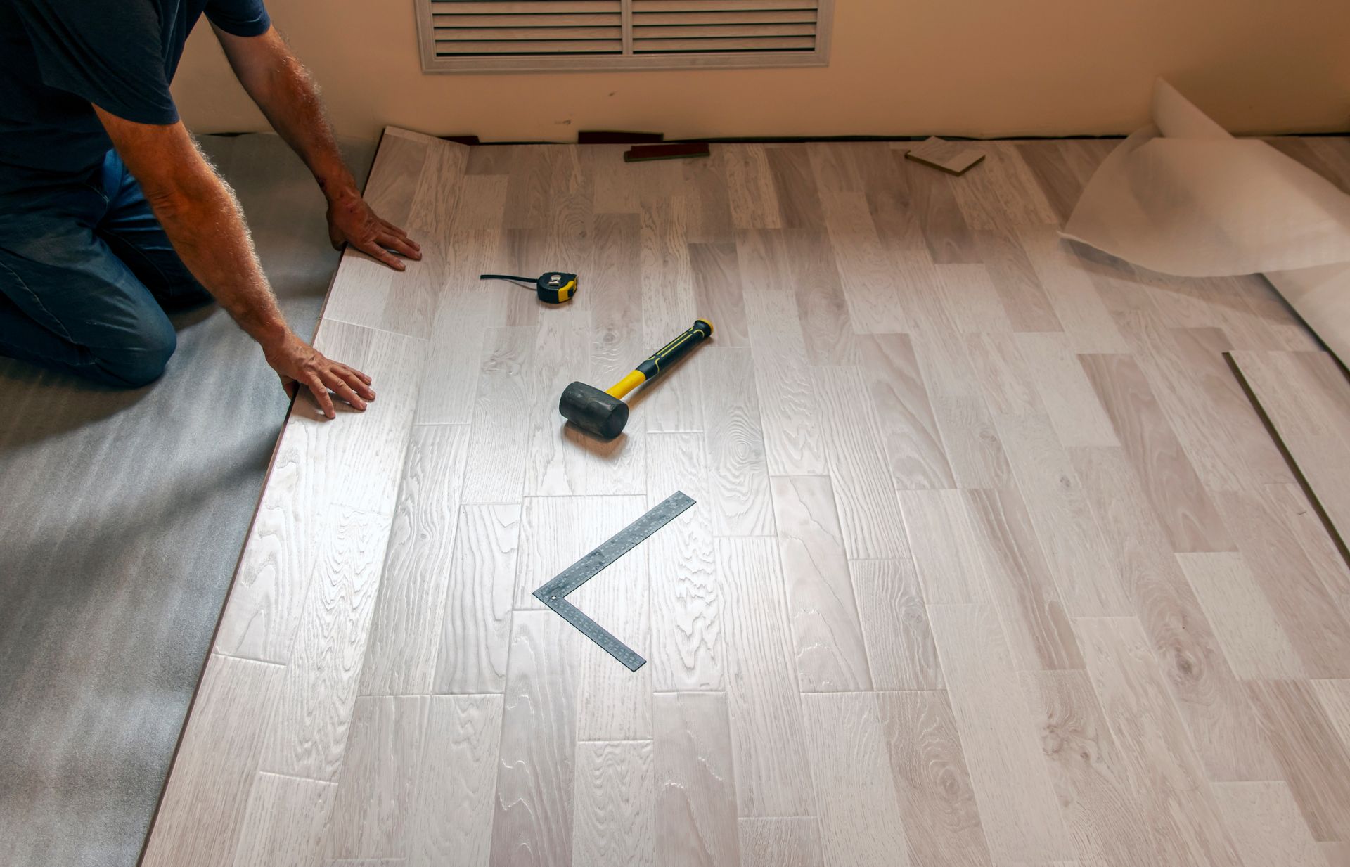 Un homme pose un parquet flottant