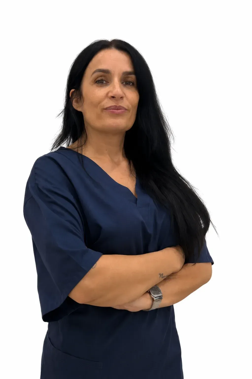Mujer con vestido azul marino y brazos cruzados, de pie sobre un fondo blanco.