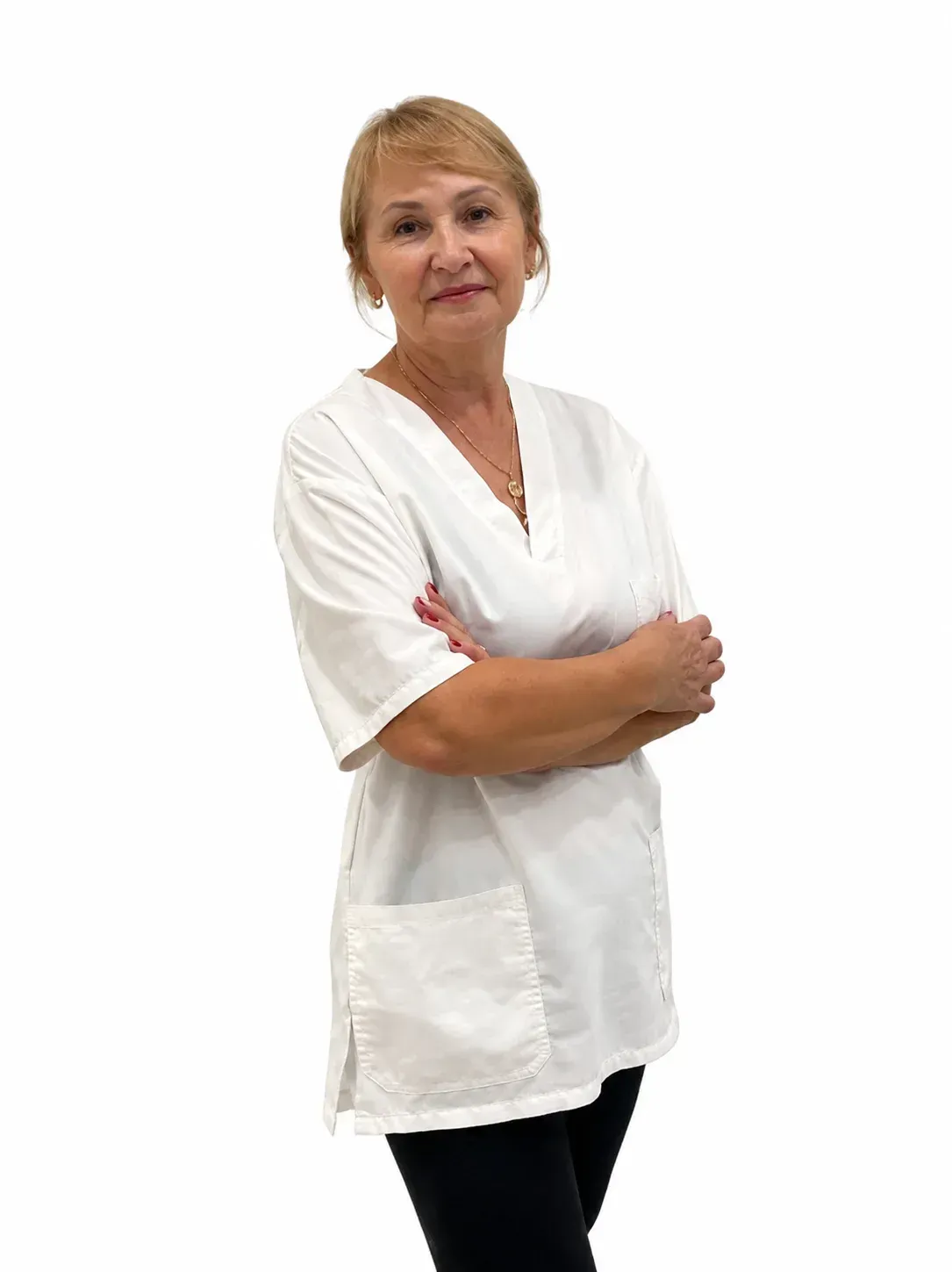 Mujer con túnica blanca de pie con los brazos cruzados sobre un fondo blanco.