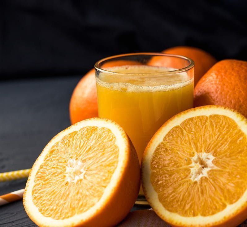 Naranjas y un vaso de jugo de naranja en una mesa