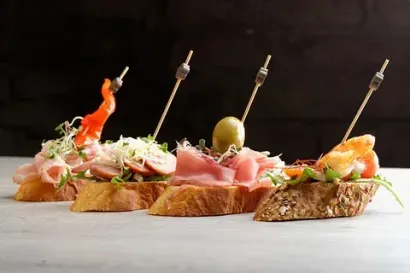 Una fila de sándwiches con carne y verduras en palillos sobre una mesa.