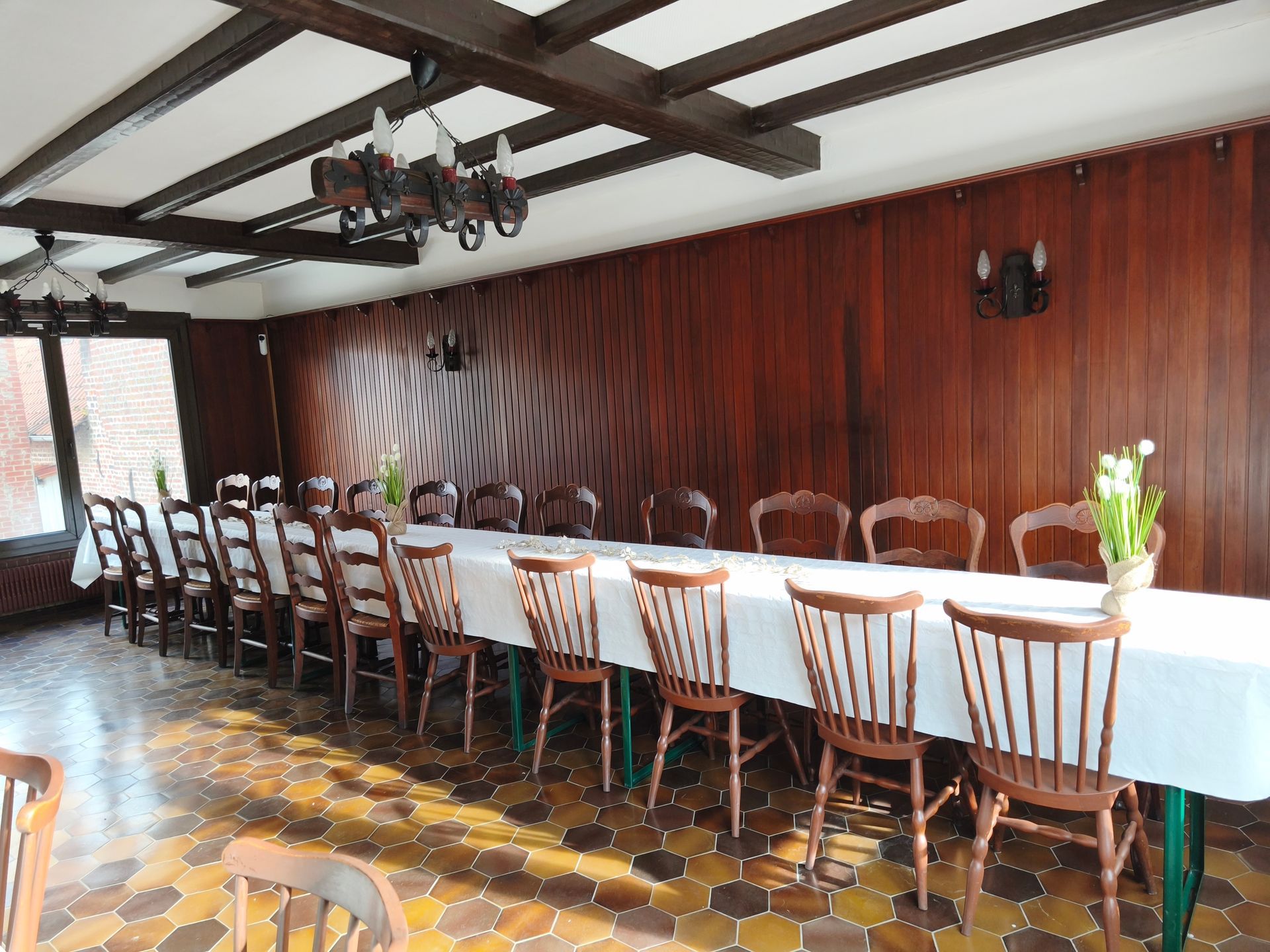 Longue table à manger avec nappe et chaises dans une salle de banquet lambrissée