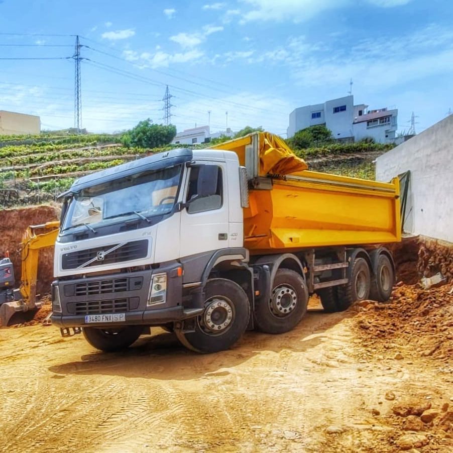 Un camión volquete amarillo está estacionado en un camino de tierra