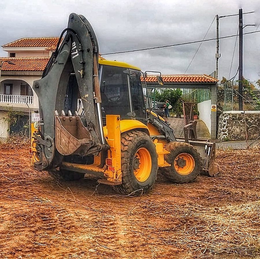 Un tractor amarillo con un balde en la parte trasera está estacionado en un campo de tierra.