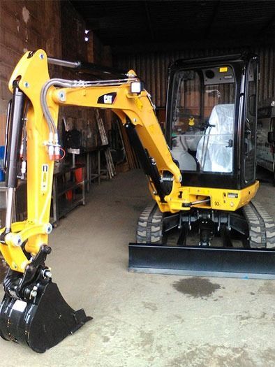 Una excavadora amarilla está estacionada en un garaje