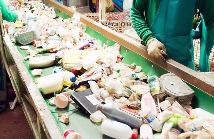 Una persona está trabajando en una cinta transportadora llena de botellas de plástico.